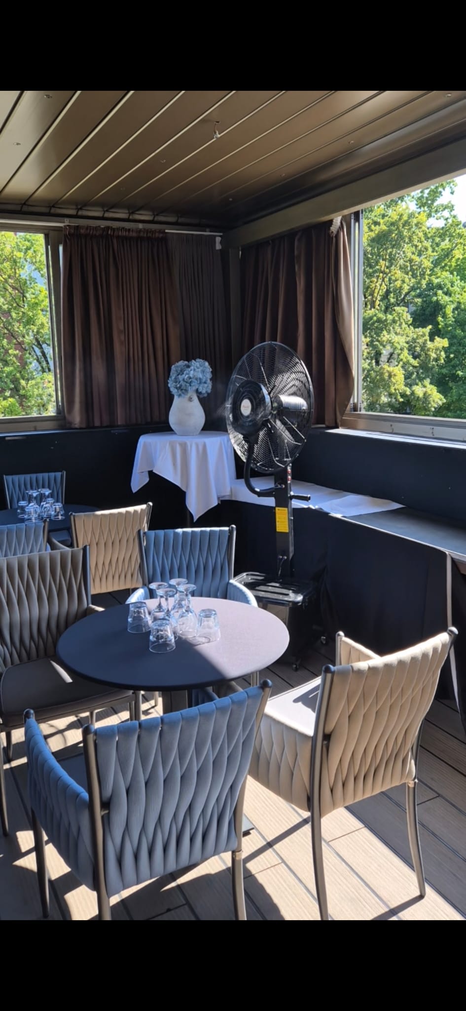 Elegantna terasa restorana s ventilatorom na vodu pored stola